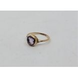 A precious yellow metal and amethyst ring, having central round mixed cut amethyst in rub-over