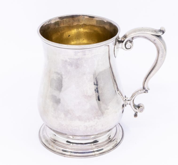 A George II plain silver baluster mug / tankard, with S-scroll handle, raised foot, gilt interior,