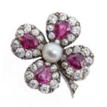 An early 20th century ruby, diamond and pearl set gold brooch in the form of a four leaf clover,