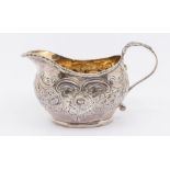 A George III silver cream jug, later profusely chased with flowers, gadroon rim, by CB?, London,