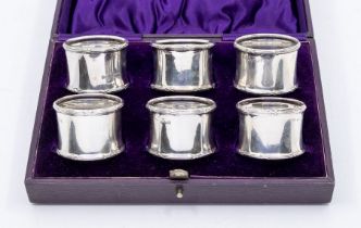 A matched set of six George V silver napkin rings, with ribbon tied reeded borders, in fitted