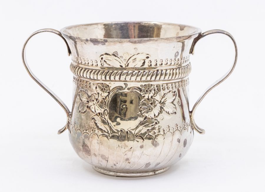 A George III silver two handled loving cup, waisted with flared rim, the body chased with flowers,