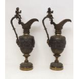 A pair of Renaissance Revival patinated bronze Cellini style ewers, each cast with a bas relief