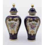 A pair of early 20th Century Royal Crown Derby vases and covers, cobalt blue grounds painted with