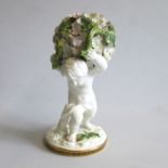 A Moore Brothers Porcelain figure of a Cherub boy holding a ball encrusted with flowers and leaves