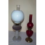 A Victorian pressed glass oil lamp and a later red oil lamp with brass base  The taller lamp stands