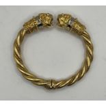 A LALAoUNIS double lion head torc in 18 carat gold, with ruby eyes (four total), plus 16 diamonds (