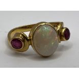 An 18 carat gold Opal and ruby set dress ring in a scroll design. Hallmarked London 1988. Size K.