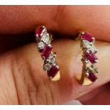 A pair of ruby and diamond 18ct gold half hoop ear studs. Each set with three baguettes of ruby