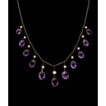 An Edwardian amethyst and half pearl gold fringe necklace, comprising graduating mixed cut oval