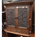 A carved reproduction oak wall hanging corner cupboard with carved panels