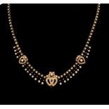 An Edwardian half pearl 15ct gold necklace, three entwined graduated hearts pearl set to the