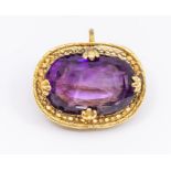 An early 20th century amethyst and yellow metal mounted brooch pendant, comprising an oval
