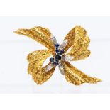 A vintage sapphire and diamond 18ct gold brooch, comprising a textured bow form with centrally set