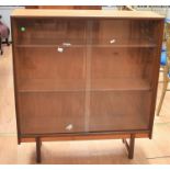 A 1970s teak glazed bookcase with two sliding doors to reveal three bookshelves