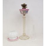 A Victorian style glass oil lamp with pink glass reservoir decorated with flowers above a facet