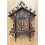 A Black Forest Trumpeter wall clock with leaf and vine carving two pine weights.