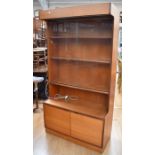 A 1970s teak display cabinet with two sliding glazed doors with three shelves above two cupboard