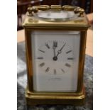 An early 20th Century giltmetal carriage clock, white enamel dial with Roman numerals, retailed by T