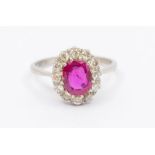 A ruby and diamond platinum cluster ring, comprising an oval cut ruby approx 1.10 carats, within a