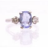 A sapphire and diamond three stone 18ct white gold ring, comprising a claw set cushion cut pale blue