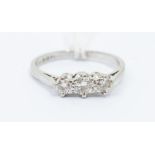 A diamond and platinum three stone ring, comprising claw set round brilliant cut diamonds, with a