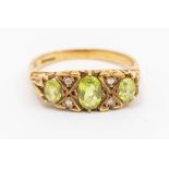 A vintage peridot and diamond 9ct gold ring, comprising three oval peridot stones with double