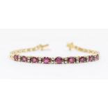 A ruby and diamond 18ct gold bracelet, comprising a row of nine claw set oval graduated rubies,