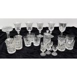 A collection of cut glass wine glasses, decanters and tumblers held in vase shaped large wicket