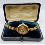 A 9 ct gold ladies 1930s watch on a gilded expandable band. The mechanism is running but the time