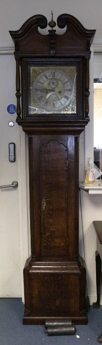 An 18th century oak longcase clock, the hood with swan neck pediments and carved wooden paterae,