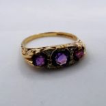 A 9ct gold amethyst three stone dress ring, with diamond chips in a carved setting. Hallmarked