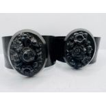 A pair of matching Victorian mourning cuffs with floral panels made from Whitby jet simulant