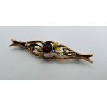 A foliate bar brooch set with seed pearls and a central garnet in yellow metal - marked 9ct. Gross