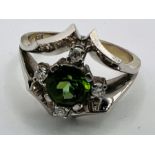 A white metal dress ring set with a green Tourmaline and four accentuating diamonds. Stamped 585.