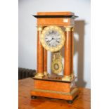 A Biedermeier maple portico clock with silvered dial, gilt metal mounts and on bun fee, 51cm high