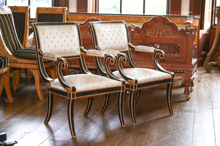 A pair of early 19th century Regency style ebonized and parcel gilt open armchairs with