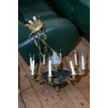 An Empire style bronze and gilt metal chandelier the central body with flame finial and issuing