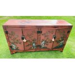 A Chinese red lacquer side cabinet decorated with birds in flowering branches with two pairs of