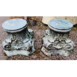 A pair of bronze cast Corinthian capitals, one with glass protector, as occasional tables, 40cm high