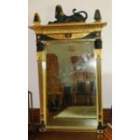 An Empire style parcel gilt and ebonized pier mirror, the top with carved sphinx above moulded