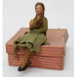 An early 20th century homemade plaster and papier-mâché doll, well modelled as a girl, seated,