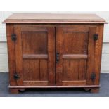 An early 20th century oak cupboard, the rectangular caddy top over two panelled doors, enclosing a