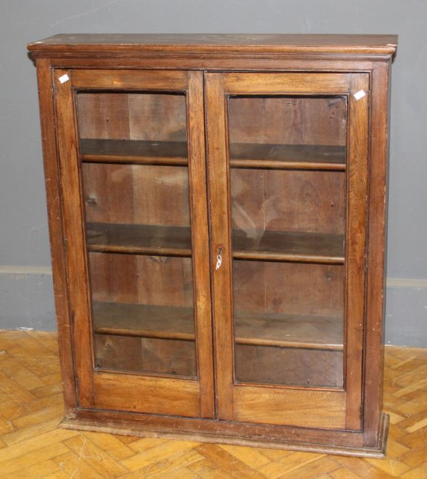 An Edwardian oak bookcase, the rectangular top over a pair of glazed doors enclosing three
