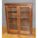 An Edwardian oak bookcase, the rectangular top over a pair of glazed doors enclosing three