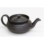 An early 19th century Staffordshire black basalt squat teapot, simple banded decoration with leaf