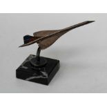 A small silver model of a Concorde airliner raised on a square marble plinth base, tail later