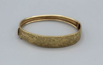 A yellow metal bangle, stamped 375, with engraved floral decoration. Gross weight approx 9.7gm
