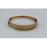 A yellow metal bangle, stamped 375, with engraved floral decoration. Gross weight approx 9.7gm