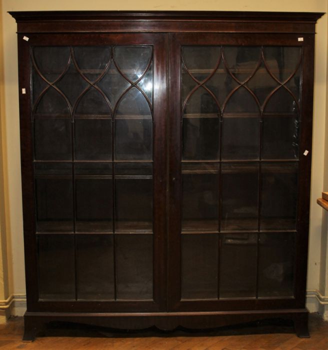 An early 19th century mahogany bookcase, the moulded cornice over a pair of shaped barred glazed